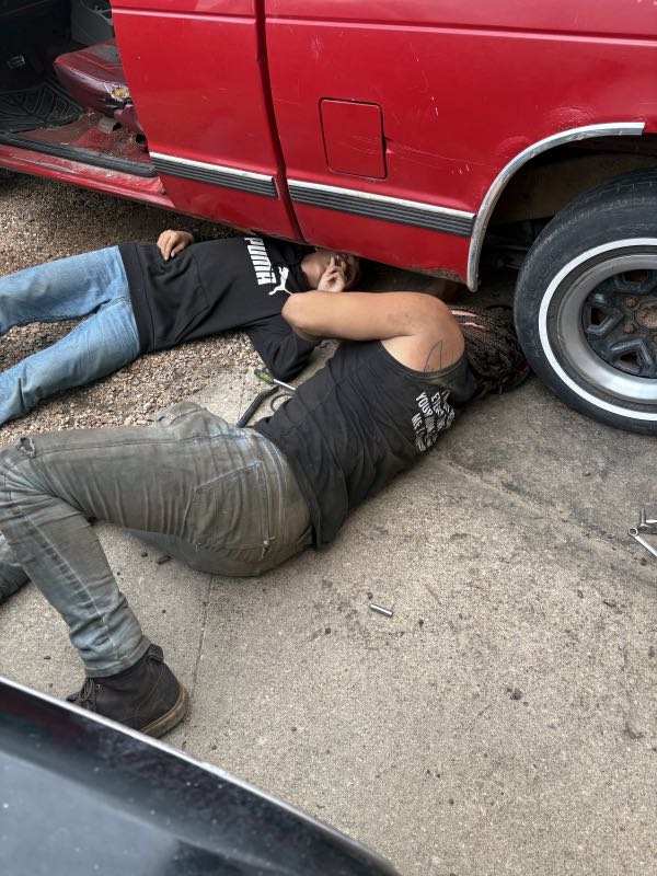 Ryan working underneath a red truck on a roadside repair
